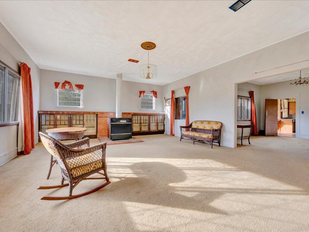 Living room with a brick fireplace, wicker rocking chairs, and a doorway to the kitchen.