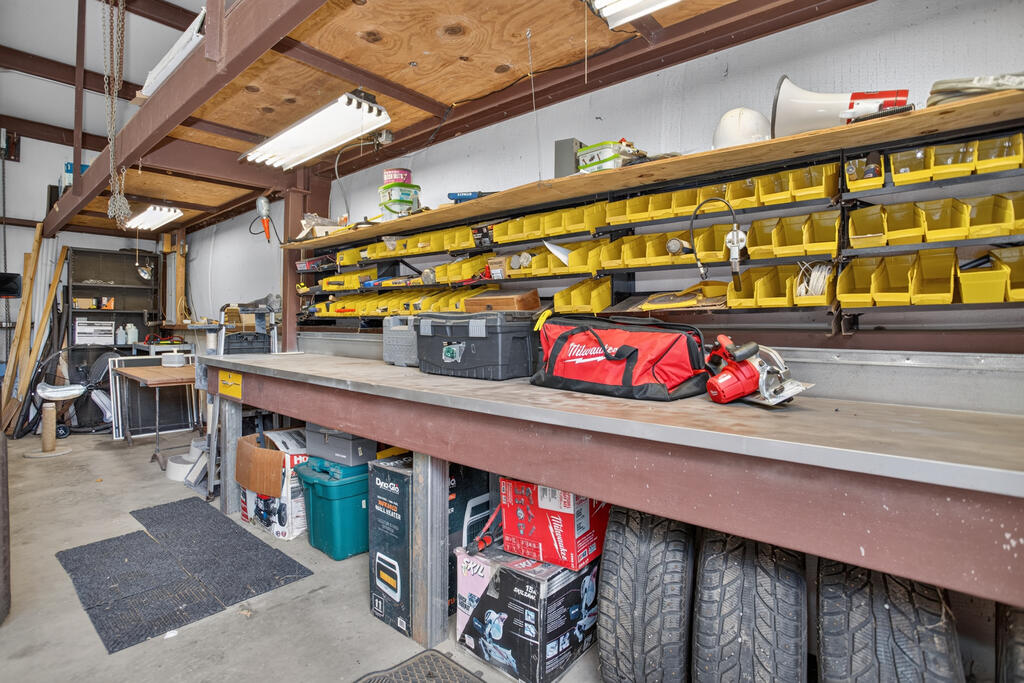 Workshop with a long workbench, yellow storage bins, power tools, and tires beneath the bench.