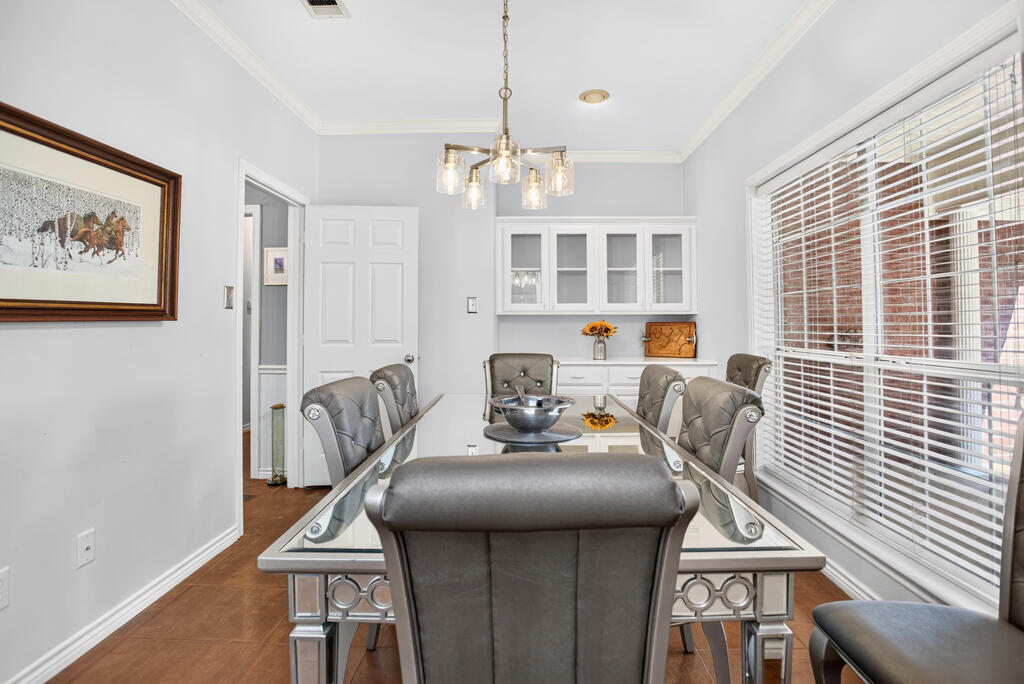 Dining room with a glass-top table, gray chairs, white built-in cabinets, and large windows.