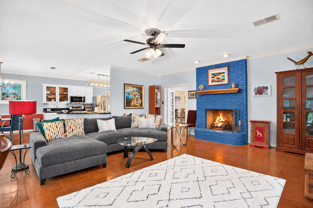 Living room with a gray sectional, blue brick fireplace, and open kitchen.