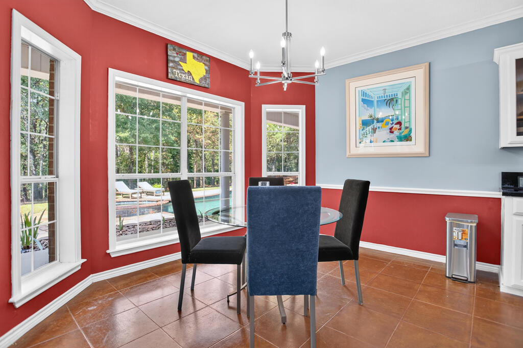 Dining room with glass table and pool views through large windows.