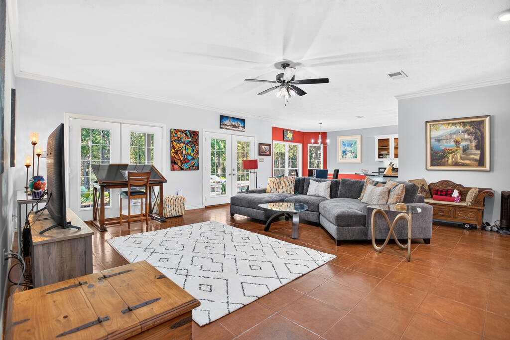 Living room with a gray sectional, patterned rug, terracotta tile floors, and French doors.