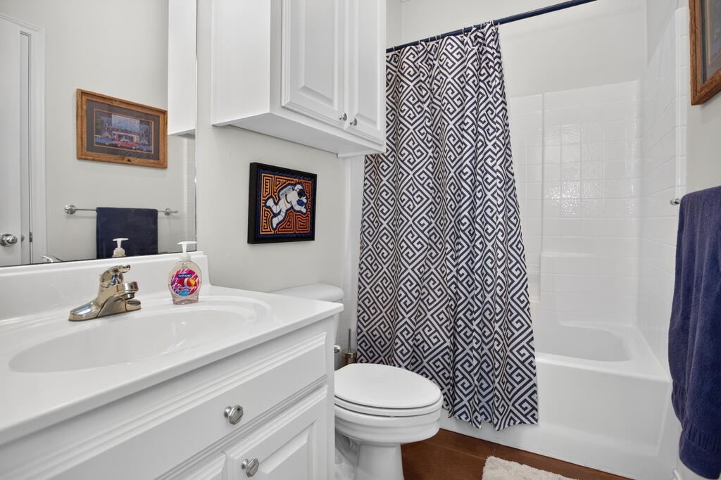 Bathroom with white vanity, toilet, and tub behind a navy-and-white geometric shower curtain.