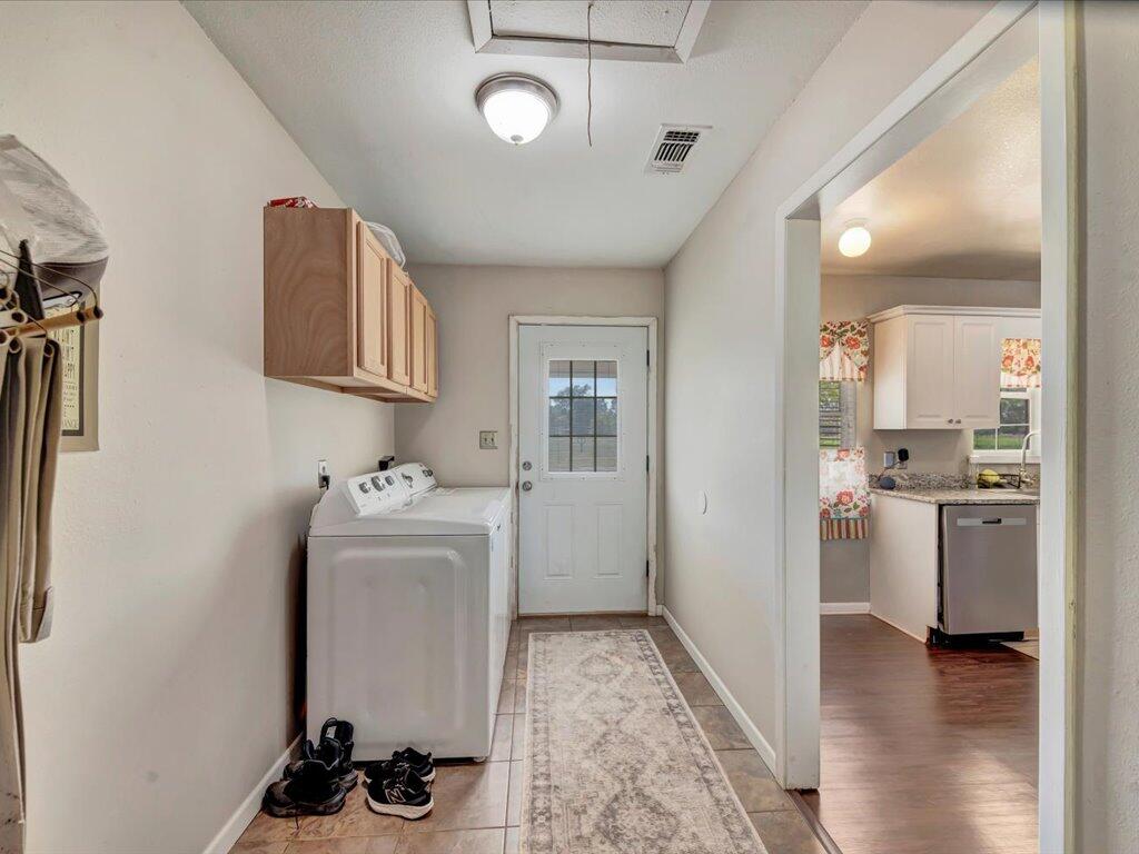 Laundry room with wall cabinets, a washing machine, and a glass-paneled door.