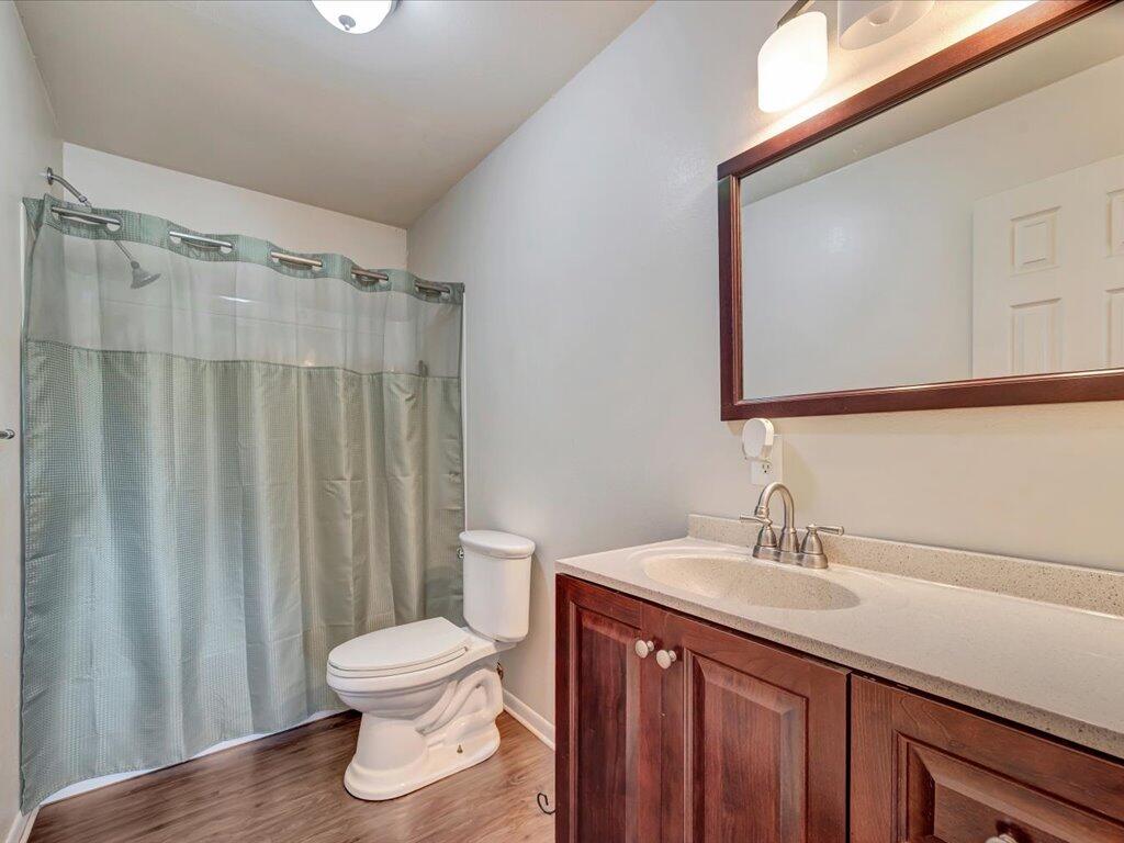 Bathroom with a pale green shower curtain and dark wood vanity.