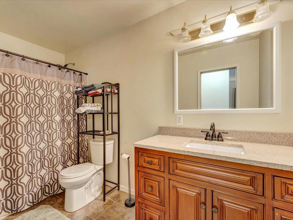 Bathroom with a wooden vanity, large mirror, and patterned shower curtain.