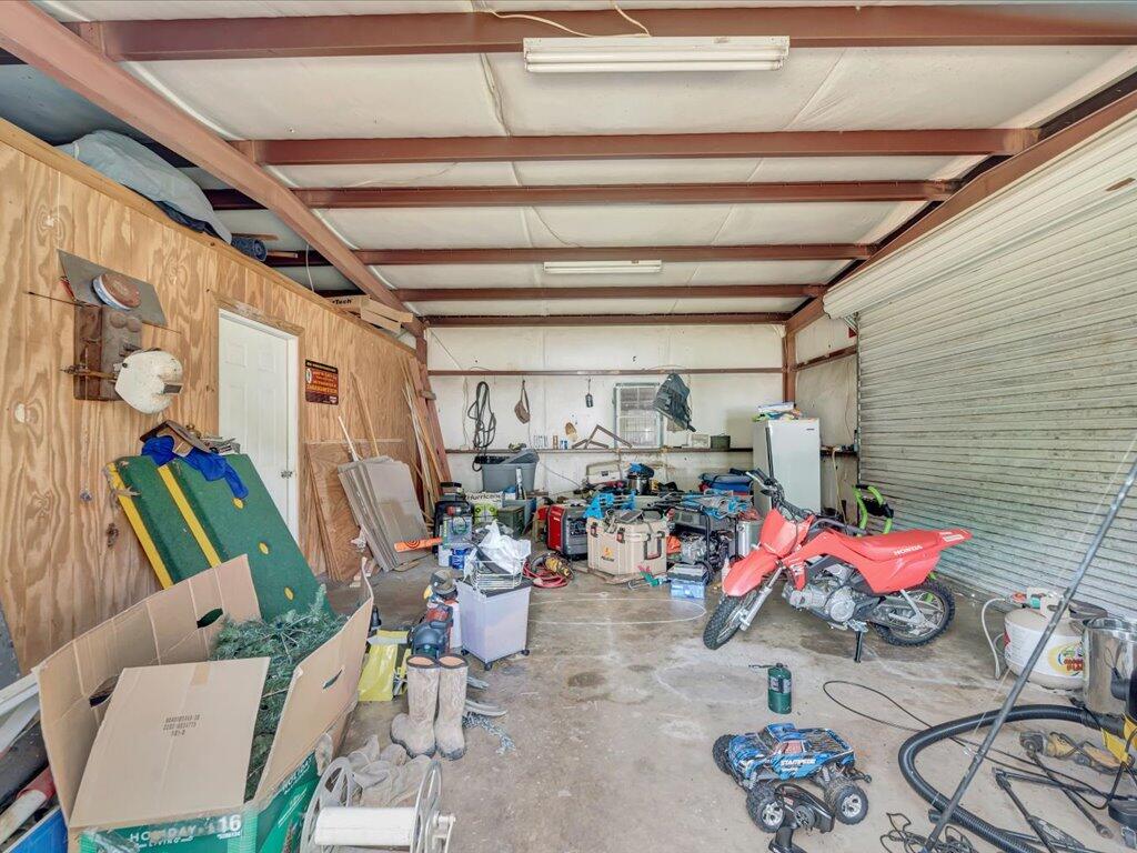 Garage workshop with a red Honda ATV, tools, and boxes beneath exposed beams.