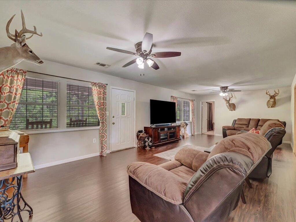 Furnished living room with brown reclining sofas, mounted deer heads, and a television.