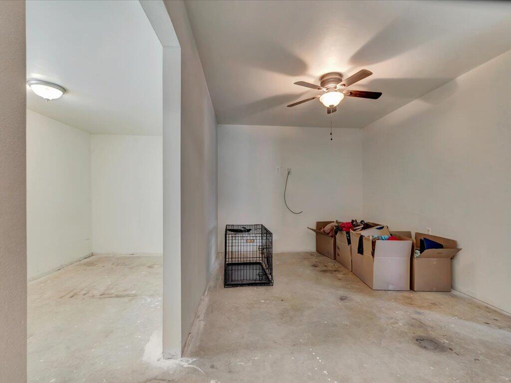 Bare garage with a concrete floor, ceiling fan, cardboard boxes, and a wire dog crate.