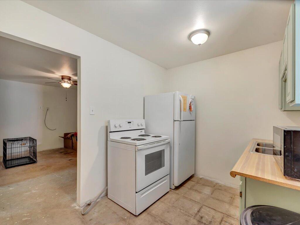 Kitchen with a white electric range and refrigerator beside a countertop sink.
