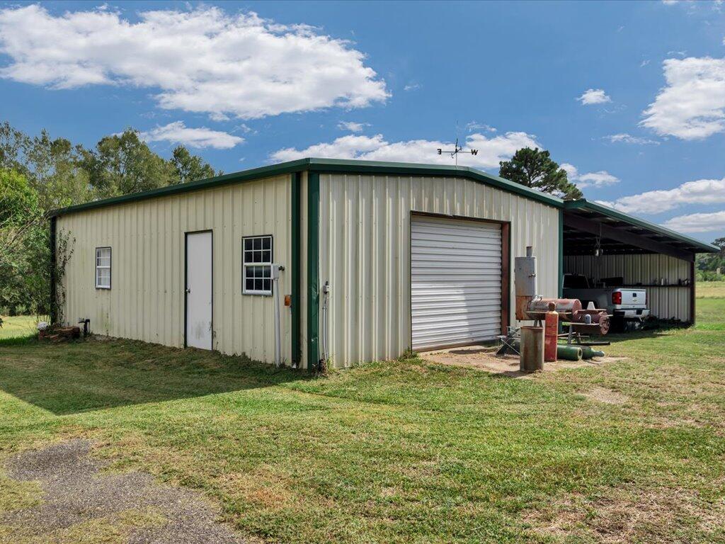 Metal workshop with a large roll-up door and an open-sided bay sheltering a pickup truck.