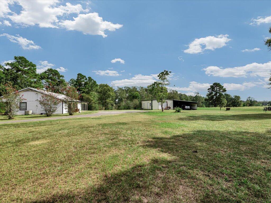 Rural property with a white home, detached metal outbuilding, and expansive grassy yard.