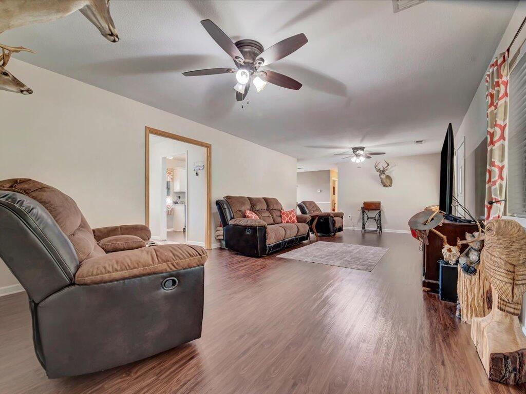Living room with brown leather seating, wood-look floors, ceiling fans, and mounted deer heads.