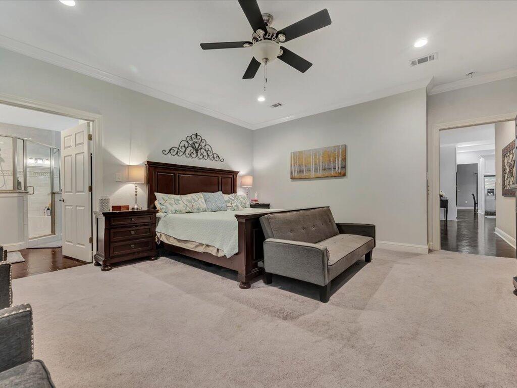 Furnished bedroom with a dark wood bed, gray loveseat, and ceiling fan.