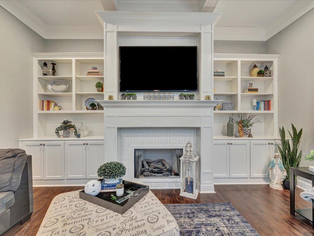 Living room with a white fireplace, built-in shelves, and a large television.