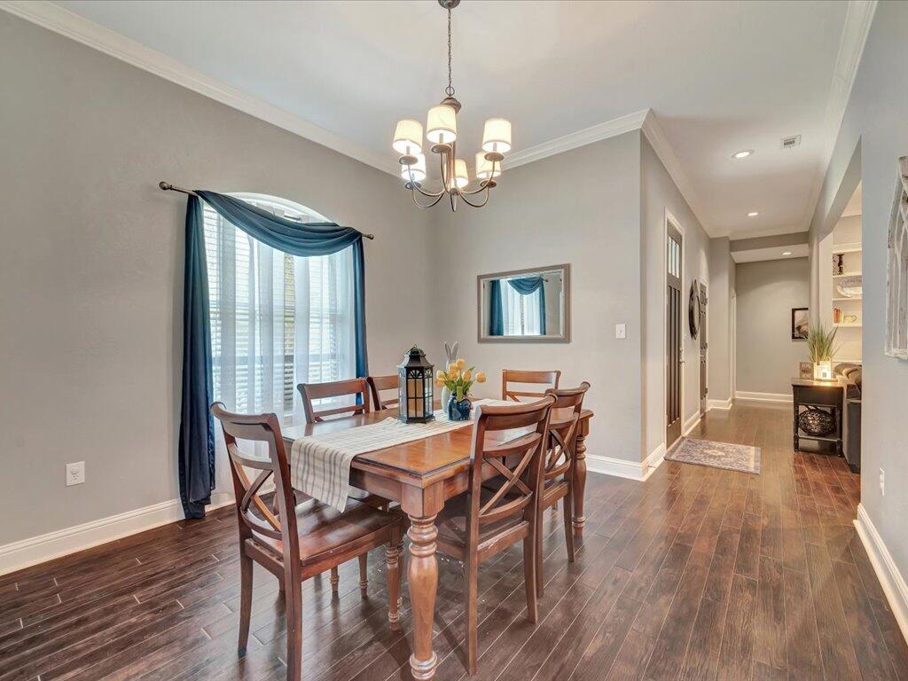 Dining room with a wooden table beneath a chandelier and a large window with blue drapes.