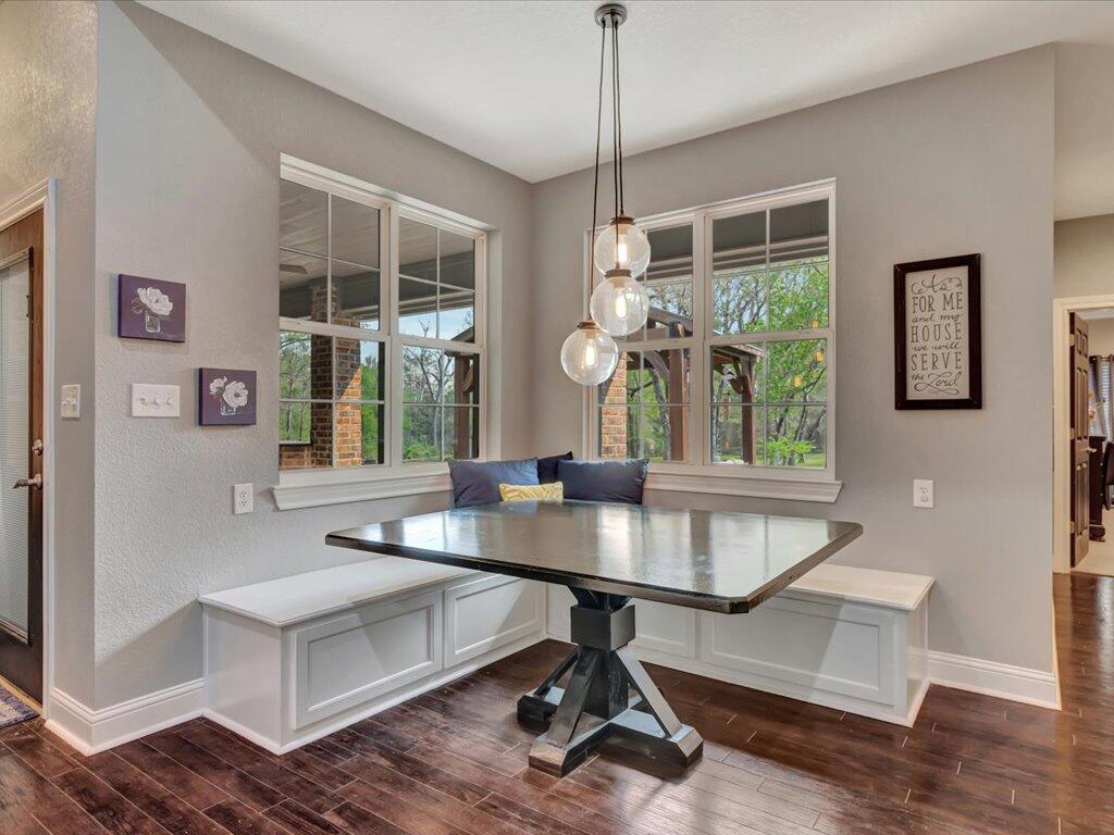 Dining nook with built-in white banquette, dark table, pendant lights, and large grid windows.