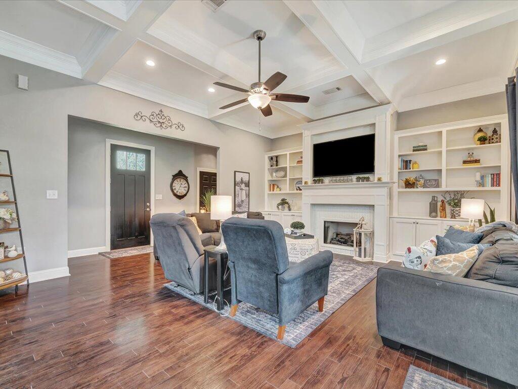 Living room with a coffered ceiling, blue-gray seating, and built-ins around a fireplace and television.