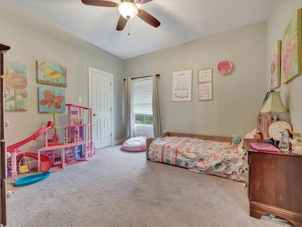 Bedroom with a floral bed, pink dollhouse playset, and colorful wall art.