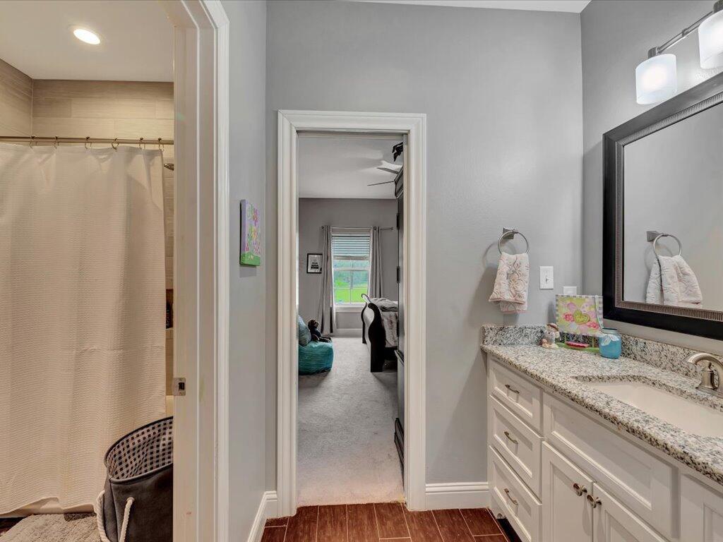 Bathroom with a granite vanity and large mirror beside a curtained shower.