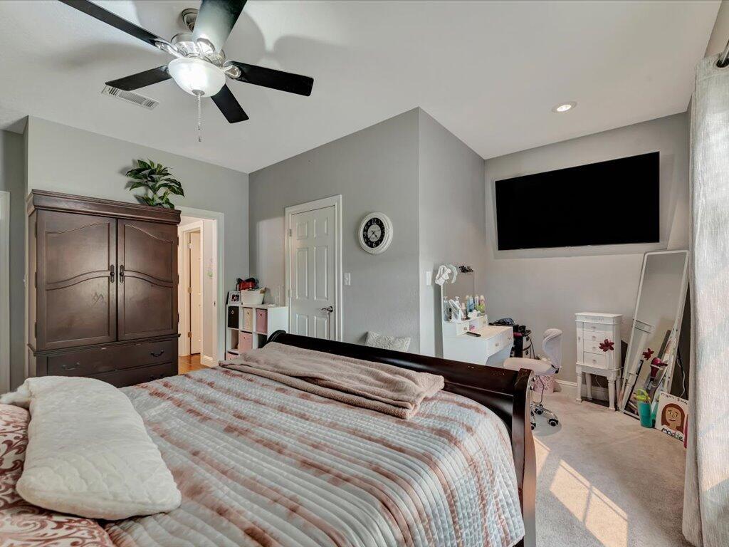 Bedroom with a large bed, dark wood armoire, and wall-mounted television.