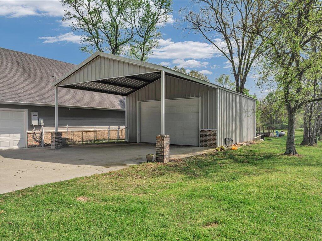 Gray metal garage with an open-sided carport beside a house.