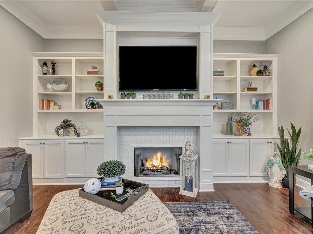 Living room with a white built-in fireplace, shelving, mounted television, and wood flooring.