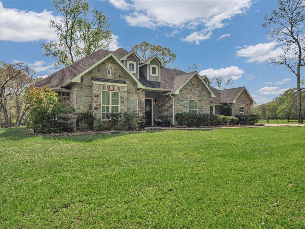 Stone-and-brick home with multiple gables and a broad front lawn.