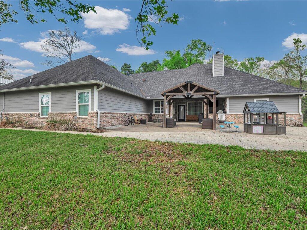 Single-story gray home with brick façade, timber-covered entry, and lawn in front.