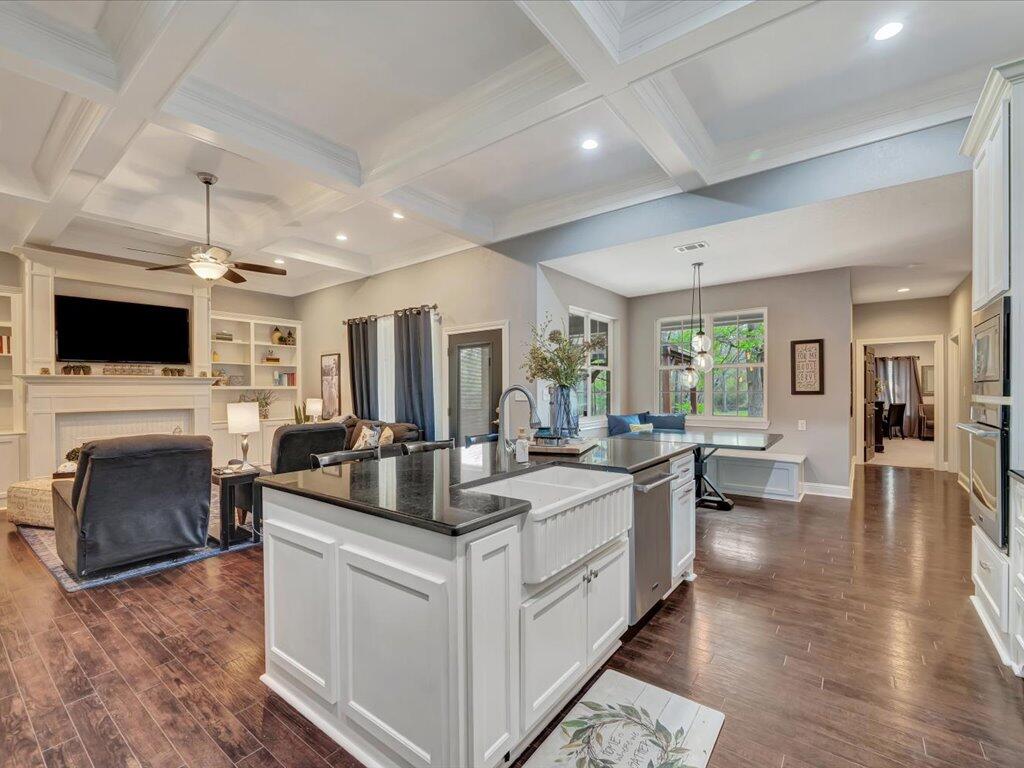 Open-plan kitchen and living room with a large island, fireplace, built-ins, and coffered ceiling.