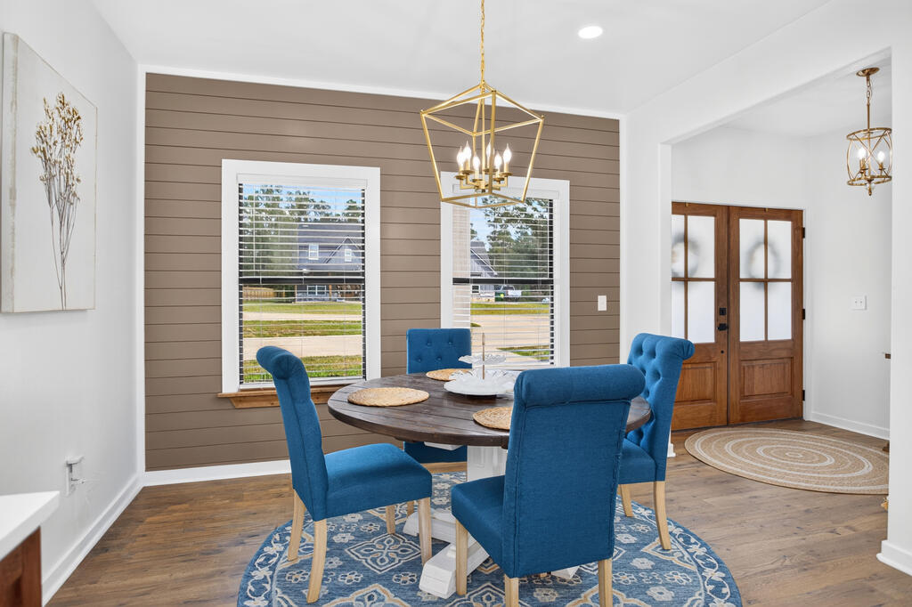 Dining room with blue chairs, a paneled accent wall, and wood-framed glass entry doors.