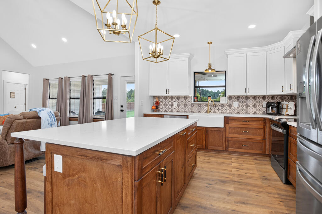Kitchen with a large wood island, white countertops, patterned tile backsplash, and stainless steel appliances.