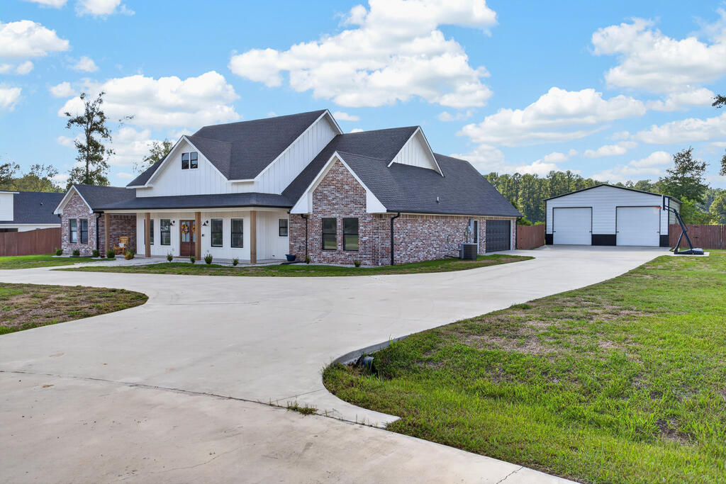 Brick-and-white house with a covered entry, curved driveway, and detached two-bay garage.