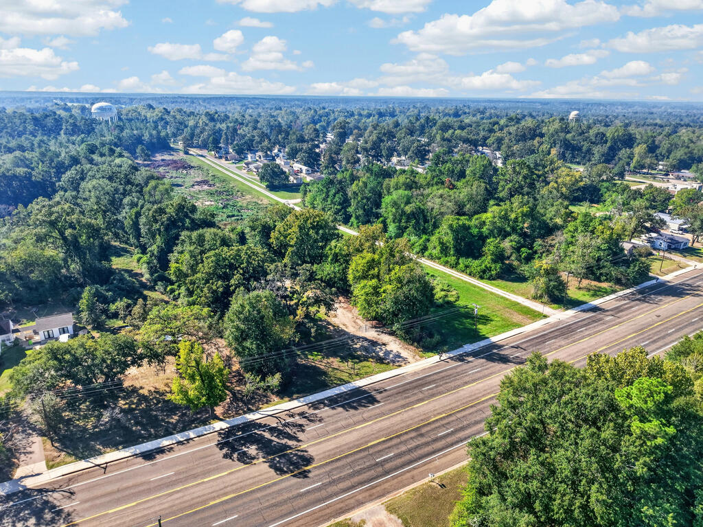 Aerial view of a wooded property with a cleared area beside a broad road.