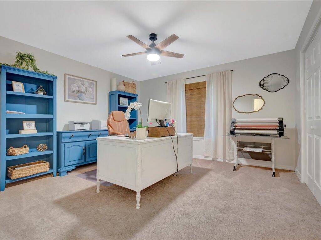 Furnished home office with a white desk, blue shelving, and a craft machine.