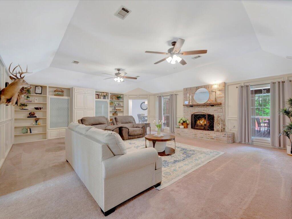 Living room with a brick fireplace, vaulted ceiling, built-in shelves, and white sectional sofa.