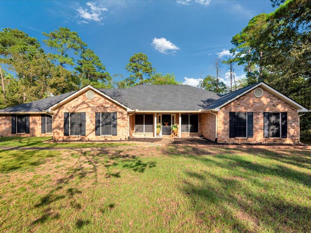 Single-story brick house with a central covered entry and broad grassy front yard.
