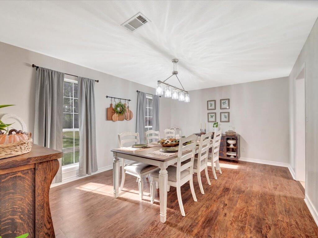 Dining room with a long white table and chairs, gray curtains, and a chandelier.