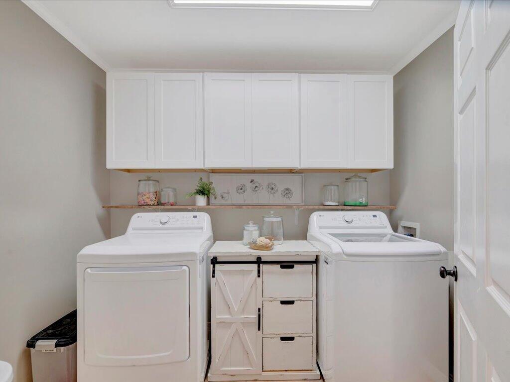 Laundry room with white washer and dryer and a farmhouse-style cabinet between them.