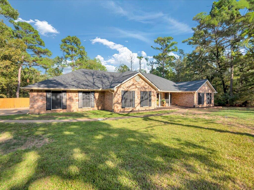 Single-story brick house with a broad lawn and mature trees.