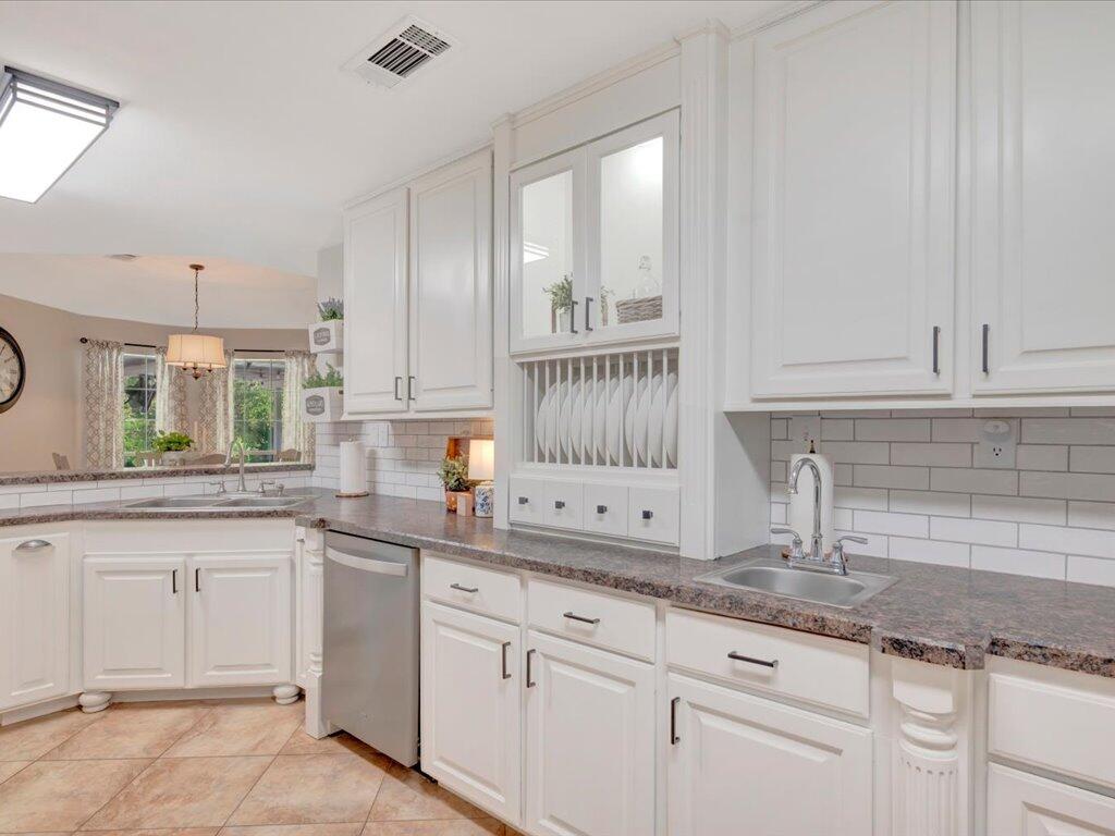 Kitchen with white cabinets, dark countertops, subway tile, and a pass-through to the dining area.