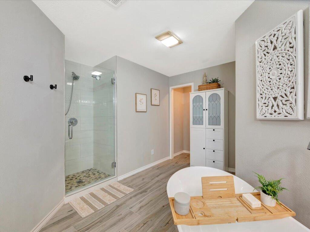 Bathroom with a glass-enclosed shower and freestanding soaking tub with a wooden tray.