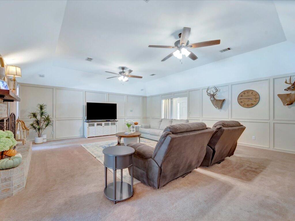 Living room with paneled walls, two ceiling fans, recliners, and mounted deer heads.