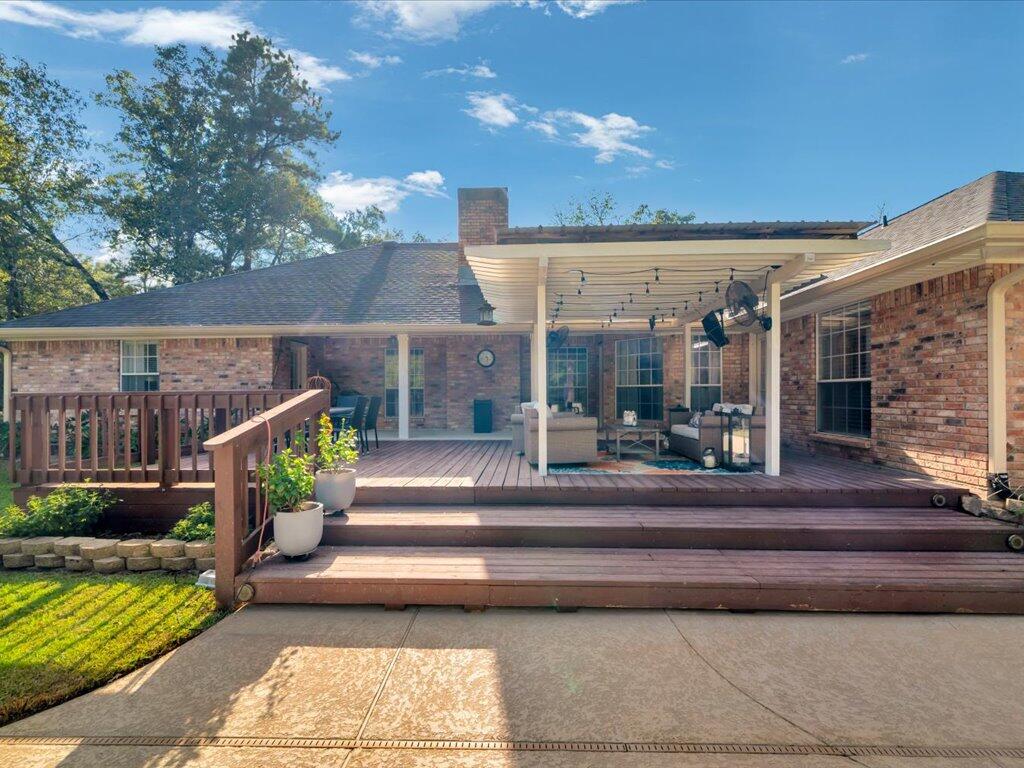 Brick home’s raised deck and covered patio with outdoor seating and string lights.