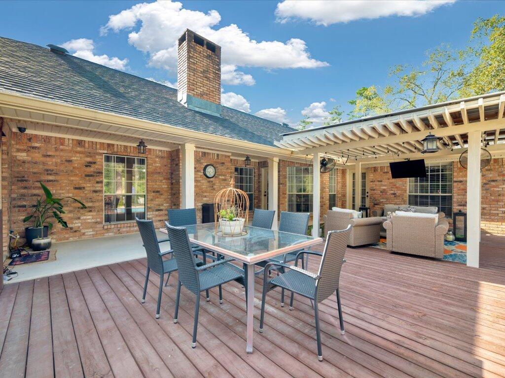 Furnished brick-home patio with a wooden deck, outdoor dining set, and covered lounge area.