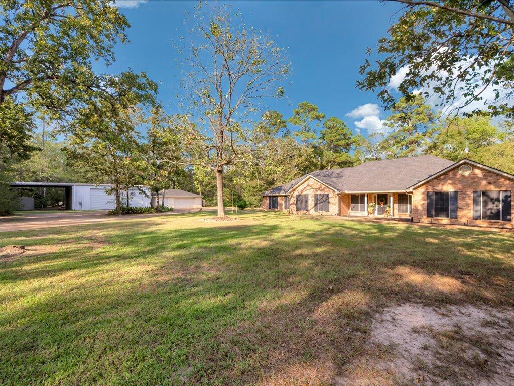 Brick house with a broad lawn and detached carport under a clear blue sky.