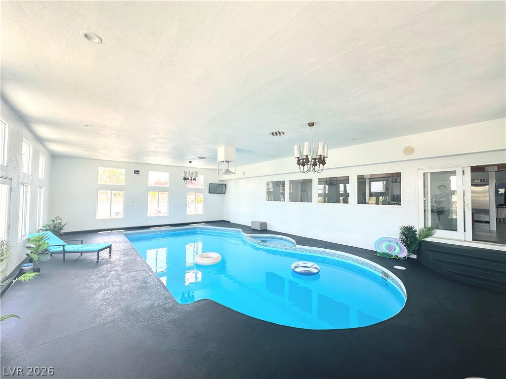 Indoor swimming pool with large windows, a dark deck, and a turquoise lounge chair.