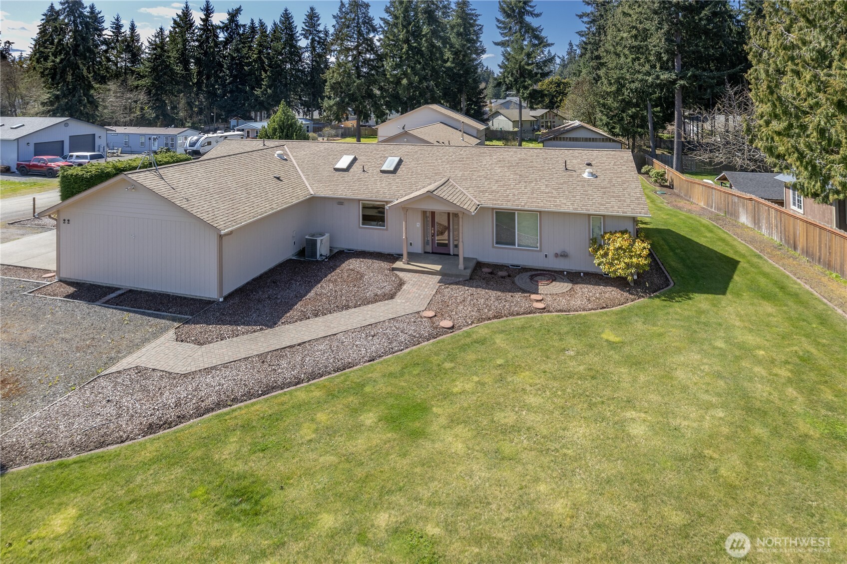 Single-story home with a broad shingle roof, paved entry walkway, and expansive lawn.