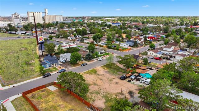 Aerial view of a vacant fenced lot surrounded by neighborhood streets and homes.