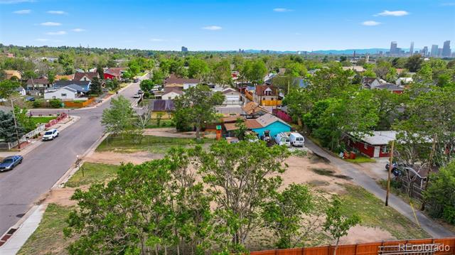 Vacant lot among Denver homes, with the city skyline in the distance.